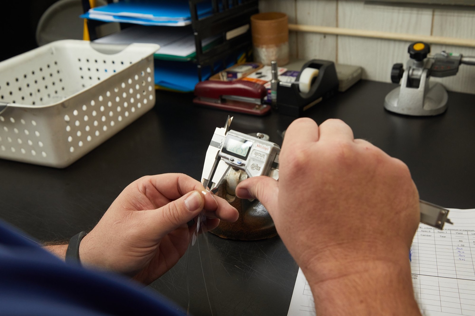 Technician measuring an extruded part with digital calipers